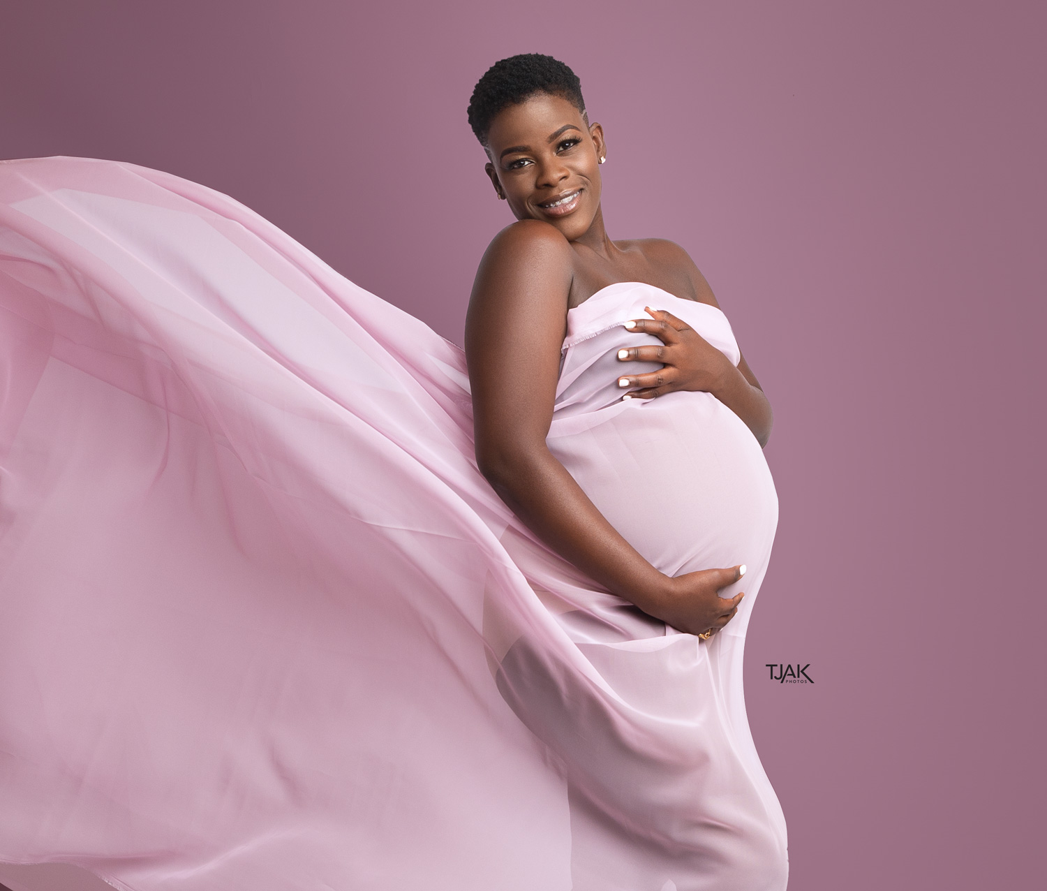 A pink flying maternity dress photoshoot of a pregnant woman in a studio in laurel maryland