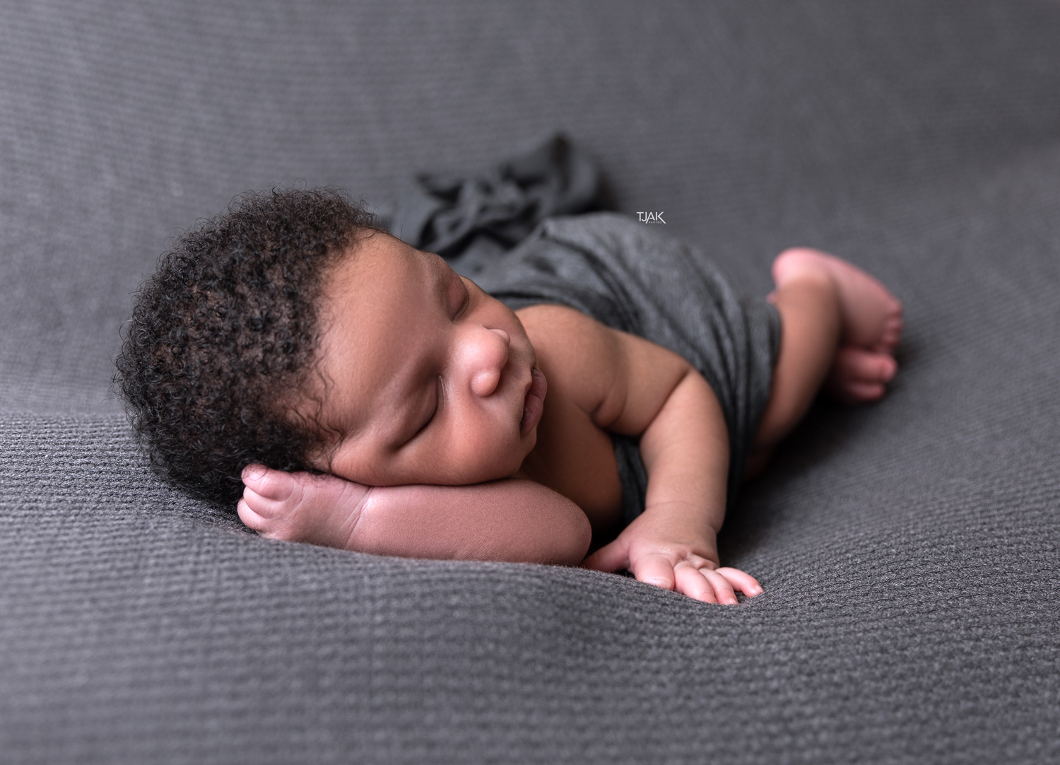 Newborn photoshoot of a baby sleeping with his hand supporting his head in a maternity photography studio near Baltimore MD