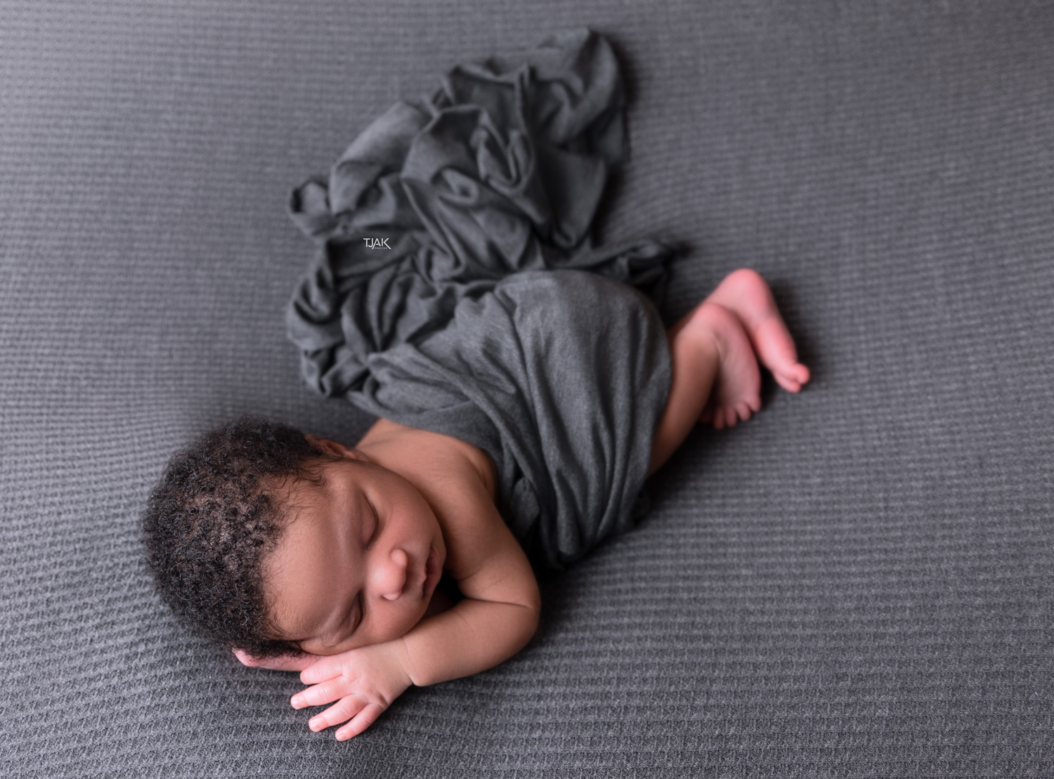 baby photograph of a newborn sleeping on a posing bag wrapped with a grey wrap in a studio in laurel Maryland