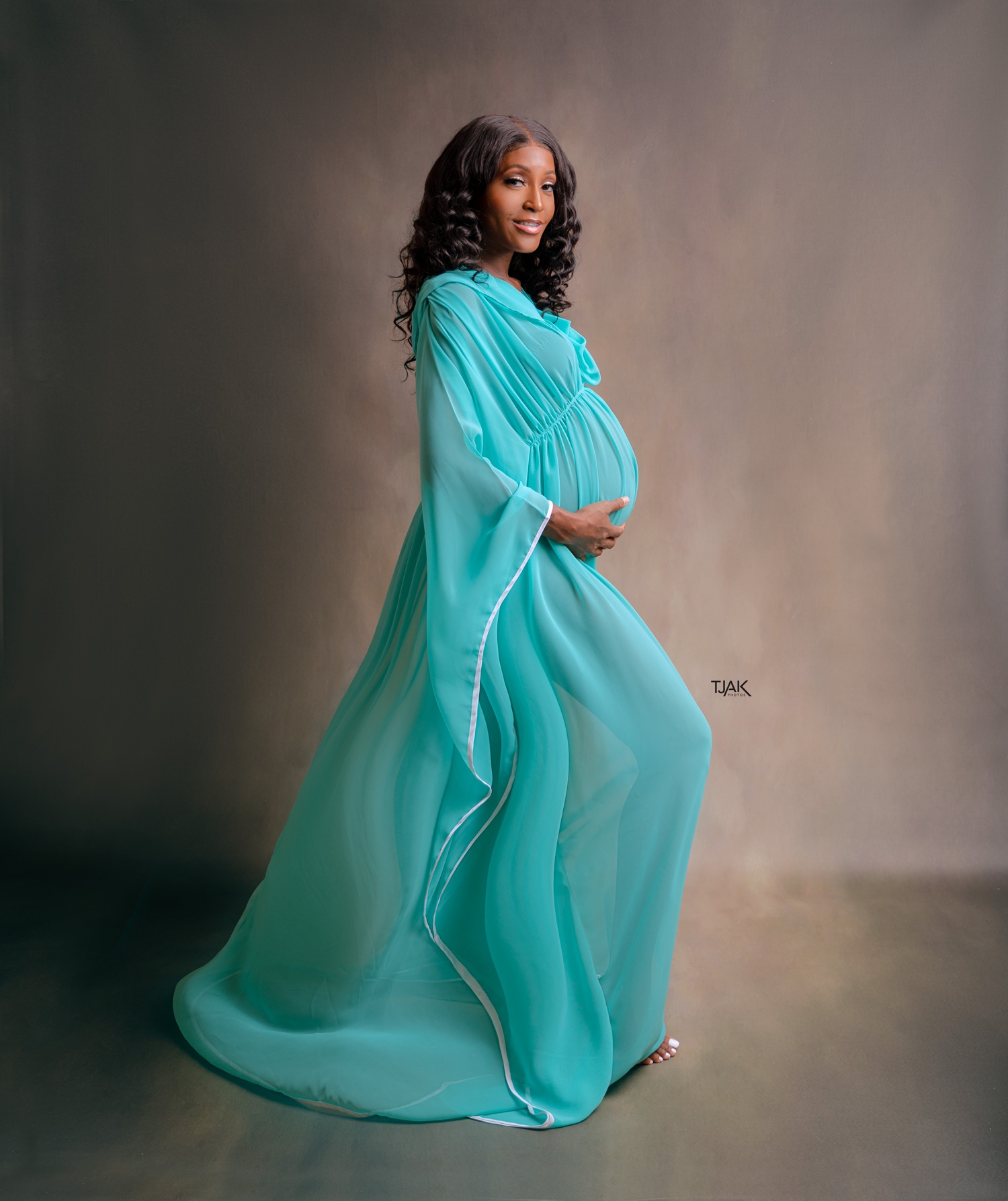 classic maternity photoshoot of a woman wearing turquoise pregnancy dress in a studio in Laurel MD near Baltimore MD in Howard County