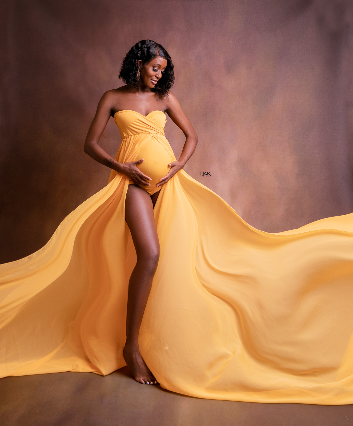 pregnancy photoshoot of a woman wearing miiestilo yellow long dress in a maternity studio in Laurel MD near Baltimore Maryland