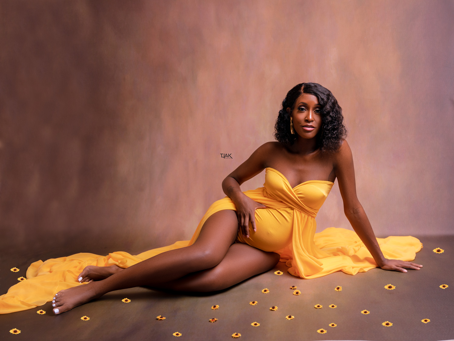 studio maternity photoshoot of a pregnant woman wearing a yellow pregnancy dress with sun flower in a studio in Laurel MD near Baltimore Maryland