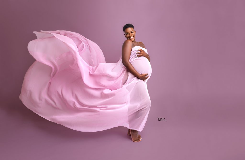 Maternity photograph of a pregnant woman wearing a pink fabric in a studio pregnancy photoshoot in Savage Maryland