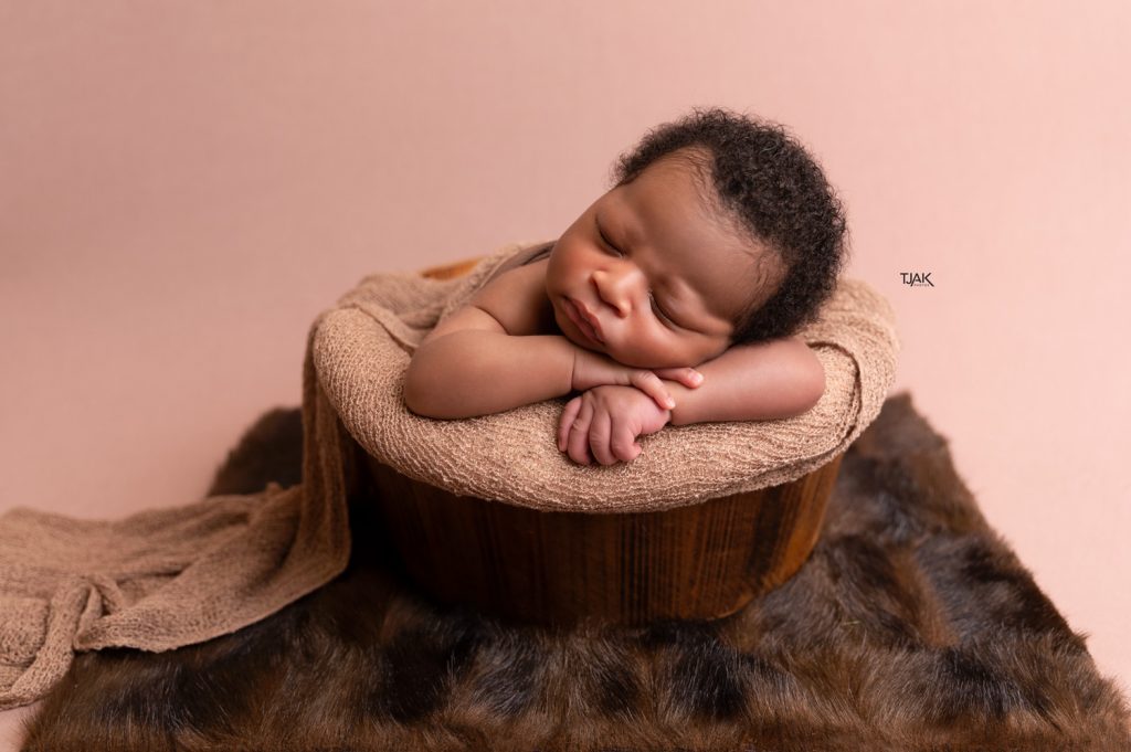 newborn photography of her baby laying on his chin in a wooden props