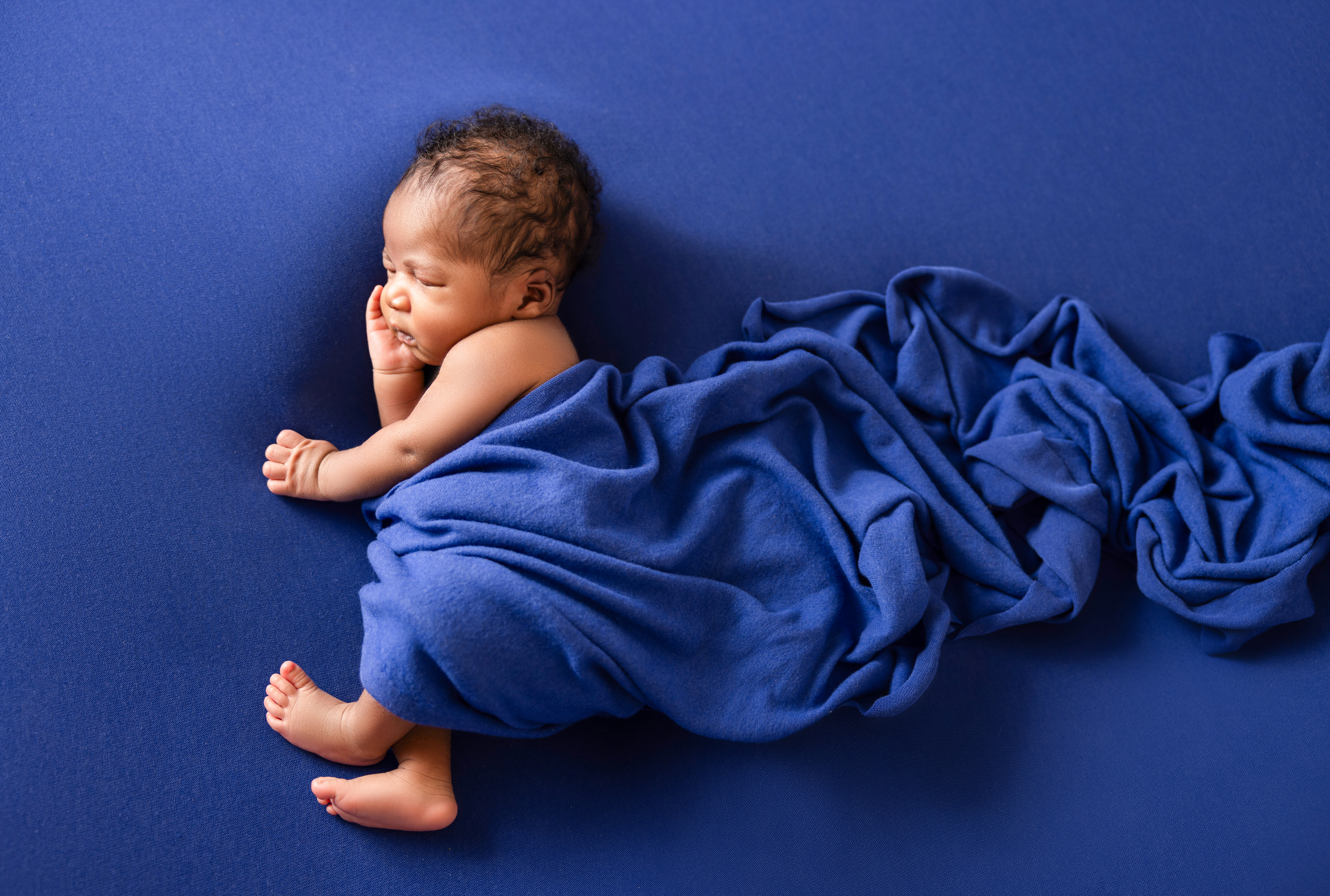 newborn photoshoot of a baby boy wrapped in blue cloth